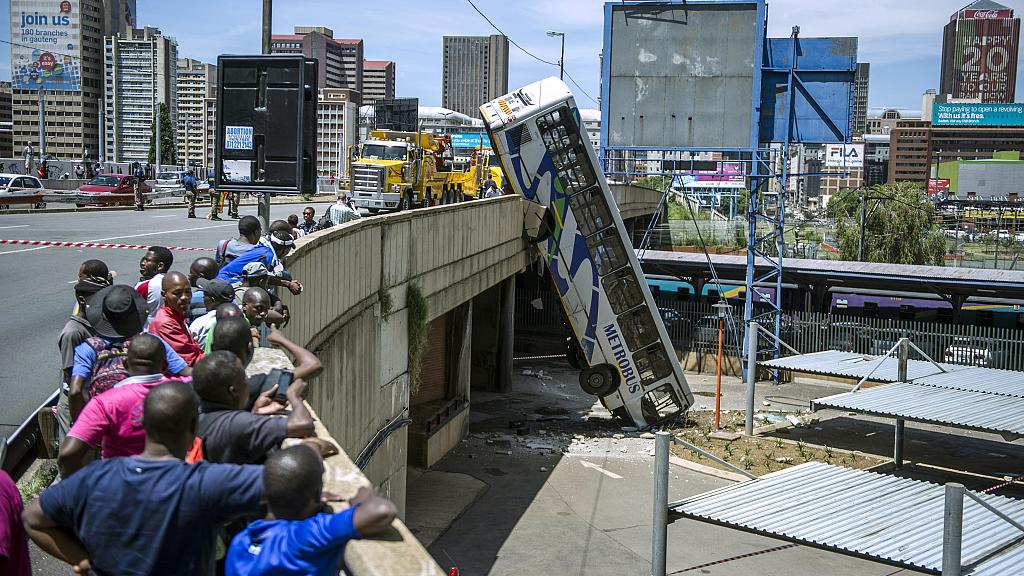 Onlookers gather on Queen Elizabeth bridge to look at a public transport bus that drove over the side of the bridge in Johannesburg, South Africa, on February 25, 2015
