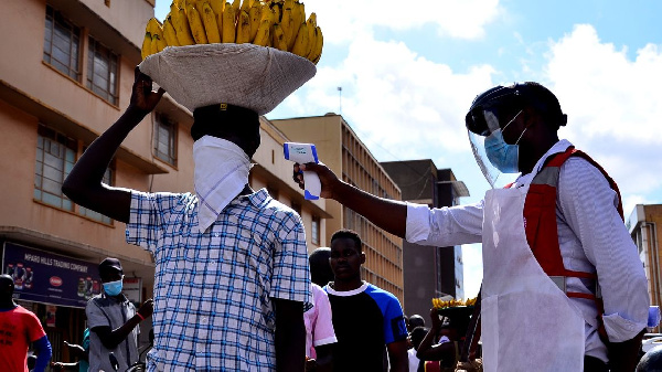 A Uganda Red Cross volunteer conducts a temperature check on a vendor in Kampala