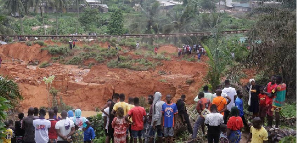 People watch an area affected by landslide after heavy rains that killed at least 13 people
