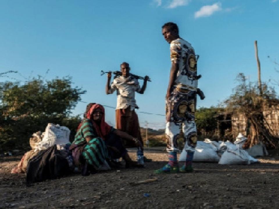 Men holding weapons stand next to a woman in the village of Bisober, in Ethiopia's Tigray region