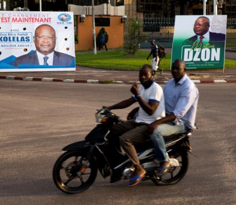 Men on a motorbike ride past billboards of presidential candidates and leading opposition leaders Guy Brice Parfait Kolelas and Mathias Dzon, in Brazzaville, Republic of Congo March 17, 2021 [Hereward Holland/ Reuters]