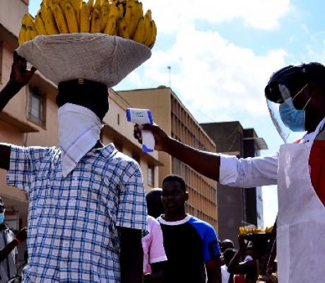 A Uganda Red Cross volunteer conducts a temperature check on a vendor in Kampala