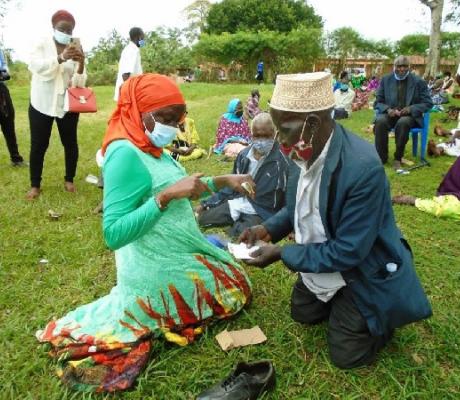 Minister for elderly affairs Sarah Kanyike (left) interacts with a SAGE beneficiary at Kayunga