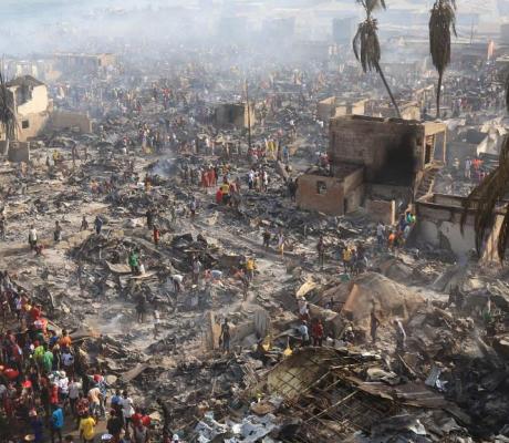 People look on at the aftermath of a large fire that broke out in an informal settlement in Susan’s Bay, Freetown on March 25, 2021